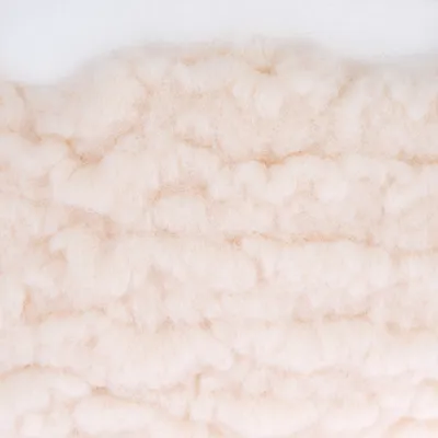 Close-up van beige, pluizig materiaal met gestructureerd oppervlak.