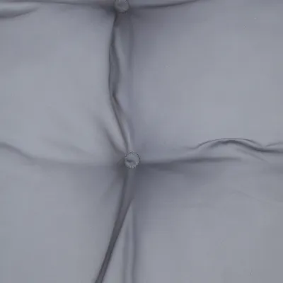 Gros plan sur un coussin matelassé gris avec boutons visibles, tissu lisse. Aucun logo ou texte apparent.