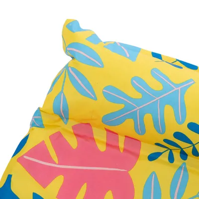 Żółty materiał z kolorowym wzorem liści w niebieskim, różowym i zielonym. Zbliżenie na wzór.