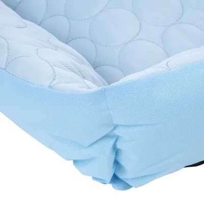 Zbliżenie na jasnoniebieski, pikowany materiał z okrągłym wzorem przeszyć. Szczegółowy widok narożnika produktu.