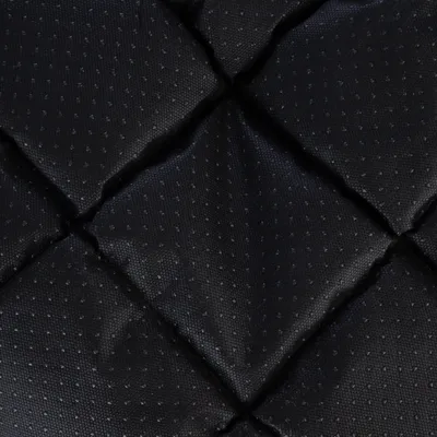 Primer plano de un material negro acolchado con superficie antideslizante y patrón de puntos.