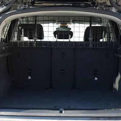 Grille de séparation en métal installée entre le coffre et les sièges arrière d’une voiture, vue depuis l’ouverture du coffre.