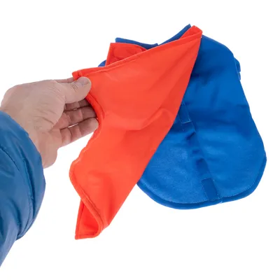 Mano che mostra una giacca per cani reversibile con un lato blu e uno arancione.