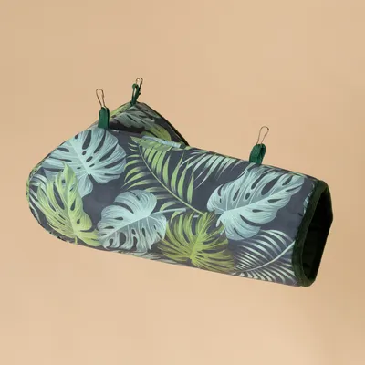 Hamaca con diseño de hojas tropicales, verde oscuro y verde claro, dos clips metálicos visibles para fijación.