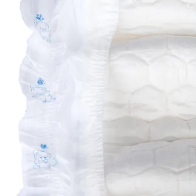 Close-up van een witte wegwerpluier met blauwe kattenmotieven en honingraatstructuur.