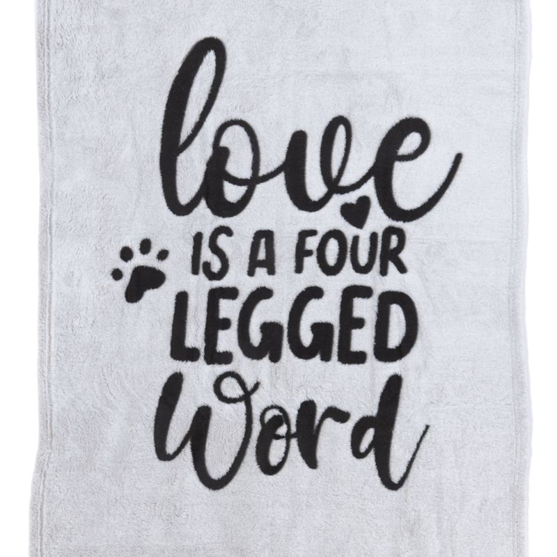 Teksti harmaalla kankaalla: 'Love is a four legged word' tassunjäljellä ja sydänsymbolilla.
