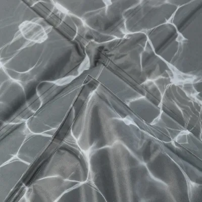 Zbliżenie szarej tkaniny z wzorem fal wodnych, odpowiednia do celów dekoracyjnych lub tekstyliów domowych.