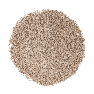 Крупный план бежевого, зернистого кошачьего наполнителя с мелкой структурой.