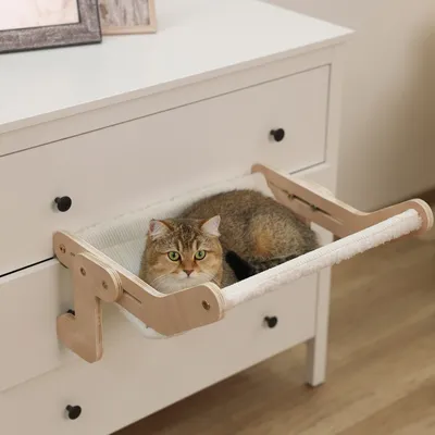 Wooden cat hammock attached to a chest of drawers with a cat lying on it. Suitable for furniture mounting.