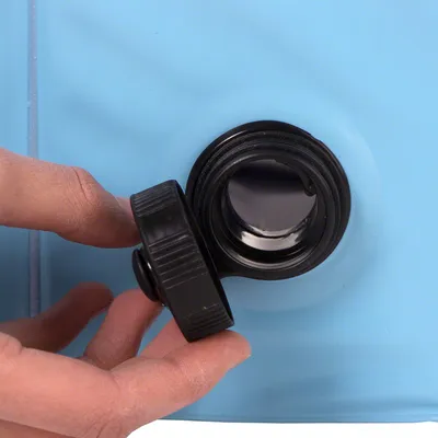 Primer plano de un tapón de rosca negro que una mano está abriendo. El tapón pertenece a un recipiente azul con una abertura grande.