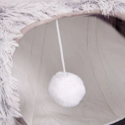 Vista interior de uma toca macia com bola de pelúcia branca pendurada por um cordão, adequada como brinquedo ou refúgio.