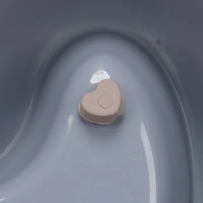 Hartvormig beige inzetstuk in een grijze kunststof kom, materiaal plastic zichtbaar.