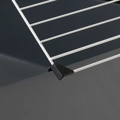 Detailaufnahme eines Käfiggitters mit weißem Metall und schwarzem Kunststoffschutz an der Ecke.