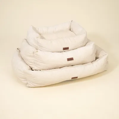 Drei beige gepolsterte Betten in unterschiedlichen Größen, jeweils mit braunem Etikett. Zeigt Größenvergleich für das Produkt.