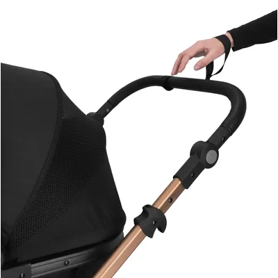 Handgriff eines schwarzen Kinderwagens mit Sicherheitsgurt, ergonomisch geformt und verstellbar. Rahmen aus Metall in Kupferfarbe.