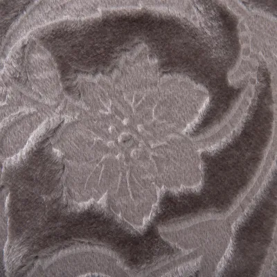 Gros plan sur un tissu en peluche grise avec motif floral en relief, matière douce et texturée visible.