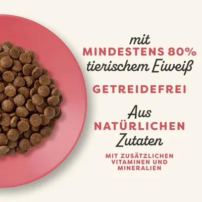 Mit mindestens 80% tierischem Eiweiss, getreidefrei, aus natürlichen Zutaten, mit zusätzlichen Vitaminen und Mineralien. Trockenfutter auf rotem Teller sichtbar.