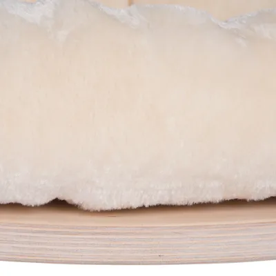Gros plan sur un coussin en tissu peluche beige posé sur une base en bois clair, sans marque visible.