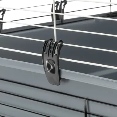 Close-up of a black clip securing the grid cover to a grey plastic tray.