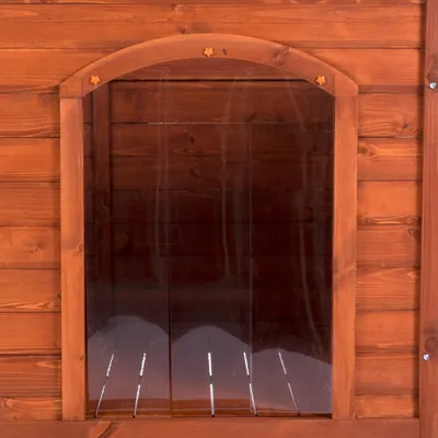 Puerta de caseta de madera para mascotas con cortina transparente de tiras plásticas verticales. Estructura y marco visibles en madera barnizada. Puerta de caseta de madera para mascotas con cortina transparente de tiras plásticas verticales. Estructura y marco visibles en madera barnizada.