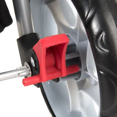 Gros plan sur une roue en plastique avec frein rouge monté sur une structure métallique, détail d’un accessoire pour animaux à roulettes.
