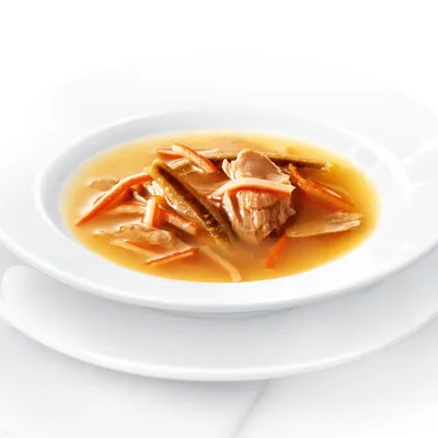 Primer plano de un cuenco con sopa, compuesta por trozos de carne y tiras de verduras en caldo claro.