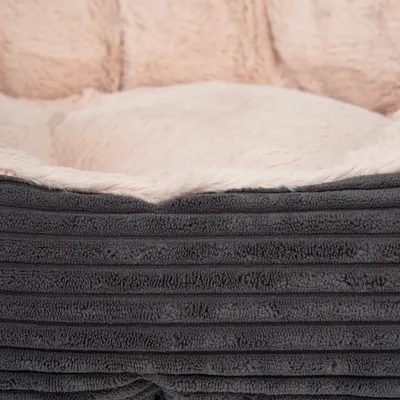 Lähikuva harmaasta, ribatusta kangasmateriaalista, jossa on pehmeä, beige plyysipehmuste. Yksityiskohtainen näkymä materiaalista ja tekstuurista.
