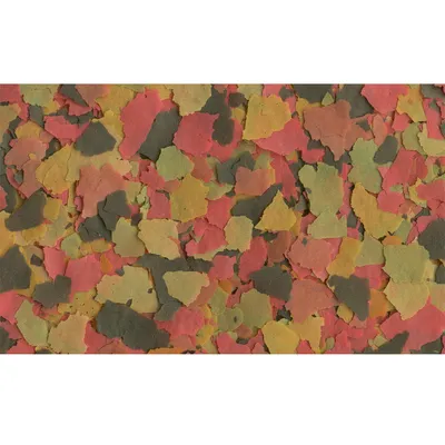 Flerfärgade flingor av fiskfoder i rött, grönt, gult och brunt, närbild utan synlig förpackning eller text.