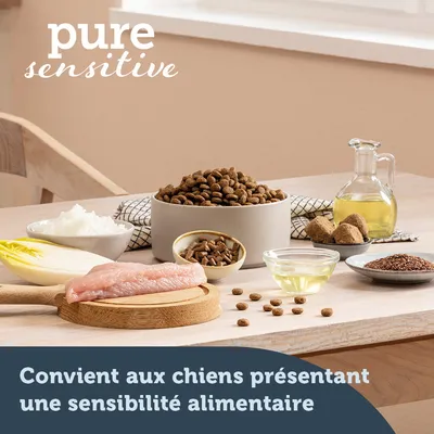 pure sensitive. Convient aux chiens présentant une sensibilité alimentaire. Ingrédients visibles : filet de viande crue, huile, riz, endive, croquettes, graines, morceaux bruns.