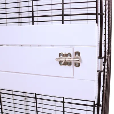 Close-up of a white metal door latch on a cage with black wire mesh walls.