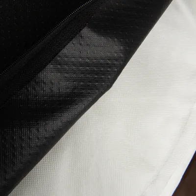Zbliżenie na czarny i biały materiał syntetyczny z widocznym zamkiem błyskawicznym. Struktura tkaniny wyraźnie widoczna.