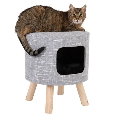 Grauer Katzenhocker mit Holzbeinen, integrierter Höhle und schwarzem Kissen. Katze sitzt oben auf dem Hocker.