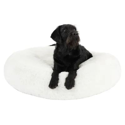 Zwarte hond ligt op een ronde, witte pluche hondenmand. Mand is zacht en heeft verhoogde rand. Materiaal: stof.