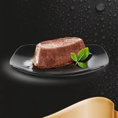 Portie natvoer in patévorm op zwart bord met twee groene blaadjes, zonder zichtbare merknaam of verpakking.