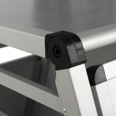 Dettaglio angolo di una struttura in metallo con giunto in plastica nera, vista ravvicinata della connessione tra i profili metallici.