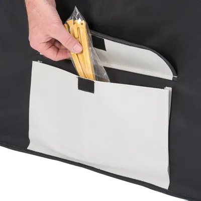 Hand stopt gele haringen in plastic zak in witte opbergvak met klittenbandsluiting aan zwarte tas of hoes. Materiaal: textiel en plastic.