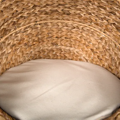 Woven basket made of natural materials with beige cushion, suitable as a lying surface.