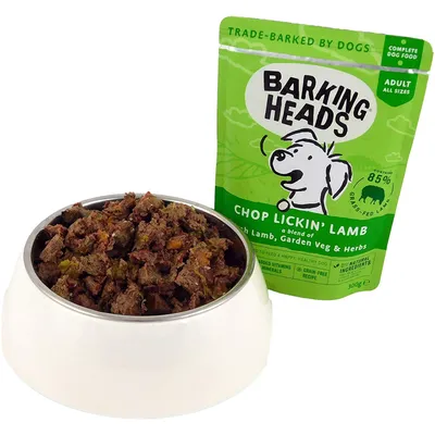 Barking Heads Chop Lickin’ Lamb complete dog food pouch for adults, shown with a bowl of the wet food. Contains 85% grass-fed lamb, garden vegetables and herbs. Grain-free recipe.
