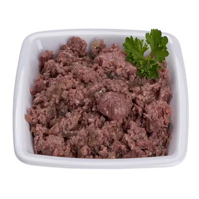 Miska s mletým mokrým krmivom pre domáce zvieratá, ozdobená vetvičkou petržlenu. Viditeľná štruktúra mäsa a omáčky.