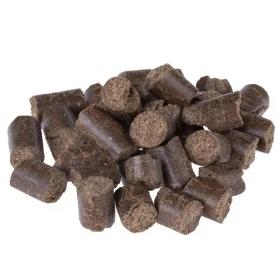 Bouchées cylindriques brunes de nourriture pour animaux, sans emballage ni marque visible, présentées en tas sur fond blanc.