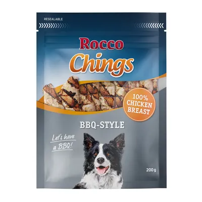 Embalagem de snacks para cão Rocco Chings BBQ-Style, 100% chicken breast, 200 g. Imagem de pedaços grelhados e cão na frente. Texto visível: Let's have a BBQ!