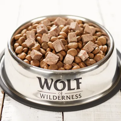 Wolf of Wilderness -kuppi, jossa ruskeita nappuloita ja lihapaloja, esillä valkoisella puupöydällä.
