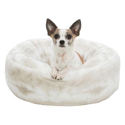 Mali pas sjedi u okruglom, mekanom krevetu od bijelog pliša. Krevet ima povišene rubove i izrađen je od tkanine s krznenim izgledom.