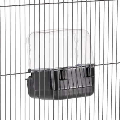 Sort foderbakke med transparent låg, fastgjort til metalgitteret på et bur.