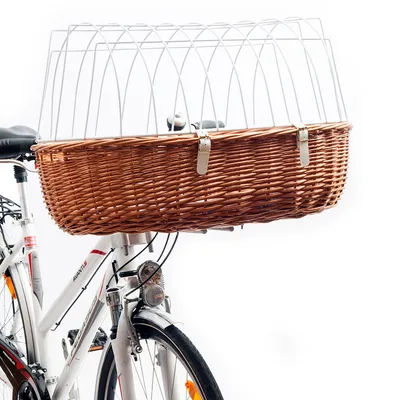 Fletkurv i brun pileflet monteret foran på cykel, med hvid metalgitter som overdækning og to læderremme til fastgørelse. Cykelens styr og forhjul delvist synlige.