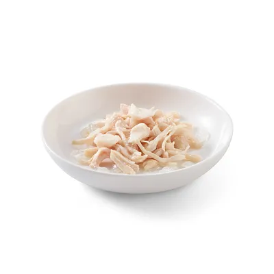 Hvid skål med fine, lyse kødstrimler i sauce, serveringsklar.
