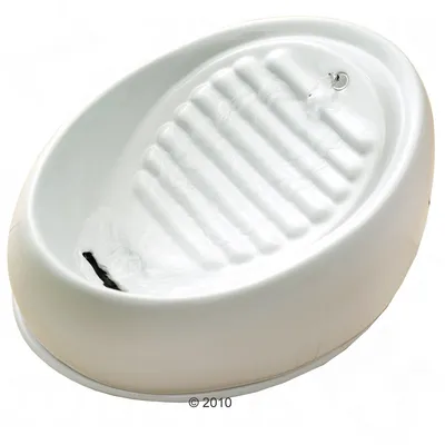 Fuente de agua blanca de plástico con superficie acanalada y chorro de agua visible en la parte superior derecha. Fuente de agua blanca de plástico con superficie acanalada y chorro de agua visible en la parte superior derecha.