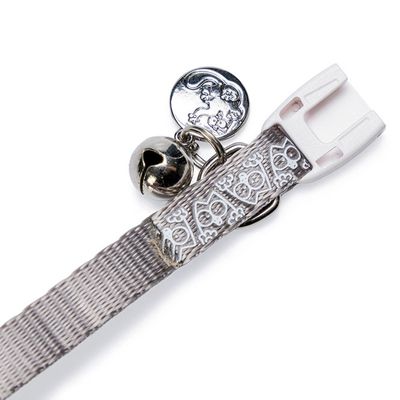 Collier pour chat gris avec motifs blancs, clochette argentée et fermoir marqué « Simon's Cat » visible sur l’étiquette.