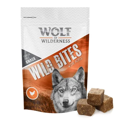 Wolf of Wilderness Wild Bites Wide Acres, graanvrije snack, afbeelding van een wolf en kip-icoon op de verpakking, drie bruine blokjes snack zichtbaar naast de zak.