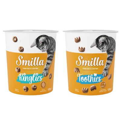 Due confezioni di snack per gatti Smilla, varianti Ringlies e Crossies da 125 g, con scritte 'with prebiotics' e 'with vitamins'. Bollino arancione con testo: Provami!